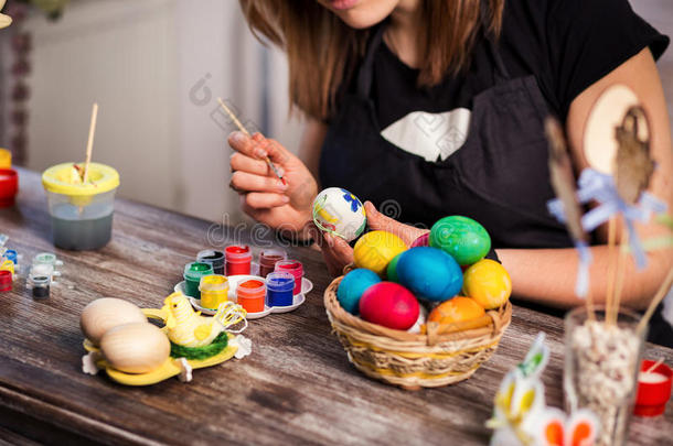 在家里为复活节着色鸡蛋。快乐的复活节！ 一个母亲，画复活节彩蛋的女孩。 幸福的家庭准备