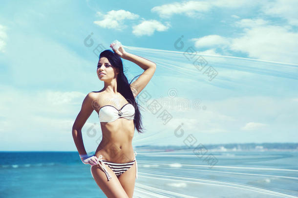 美丽的女孩穿着泳衣在海滩上摆姿势。 旅游，度假，度假，概念。