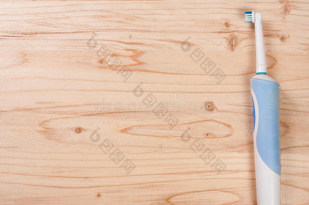 木制背景上的电动牙刷，为您的文本提供复制空间。 上面的风景