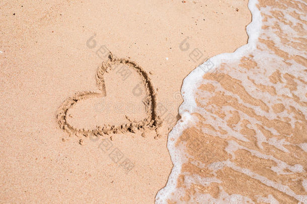 在美丽的海景背景下，在黄沙上画<strong>一颗</strong>心。