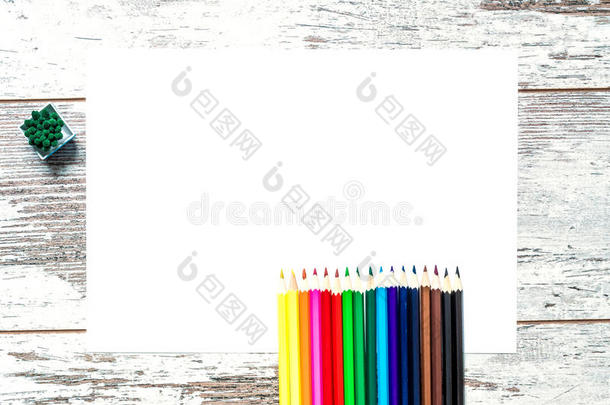 彩色五彩铅笔，一张老式木制背景上的白纸，有裂缝的木制破旧木板。