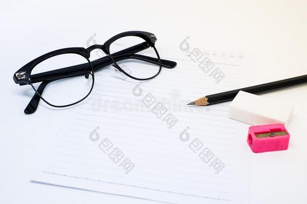 黑的眼镜,白色的纸,铅笔,粉红色的卷笔刀和橡皮擦
