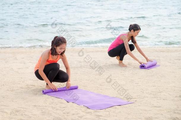 瑜伽学生保持瑜伽席子后的完成户外的海滩班,恢复健康的状态