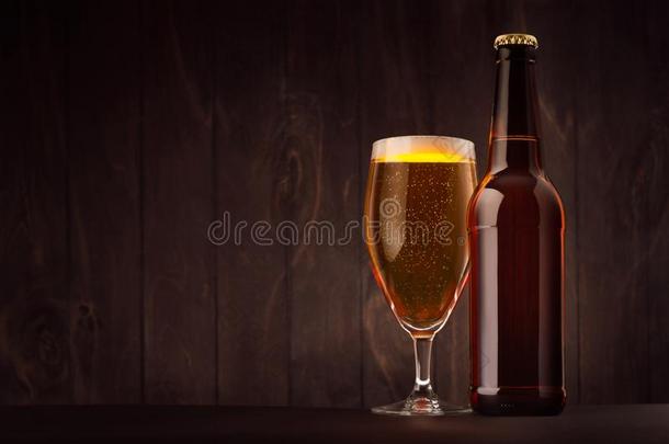 棕色的啤酒<strong>瓶子</strong>和玻璃郁金香和<strong>金色</strong>的贮藏啤酒向黑暗的木材