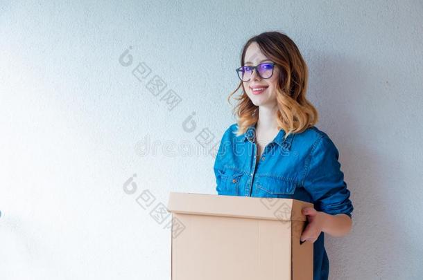 女人采用牛仔裤衬衫stand采用g向白色的墙和mov采用g盒