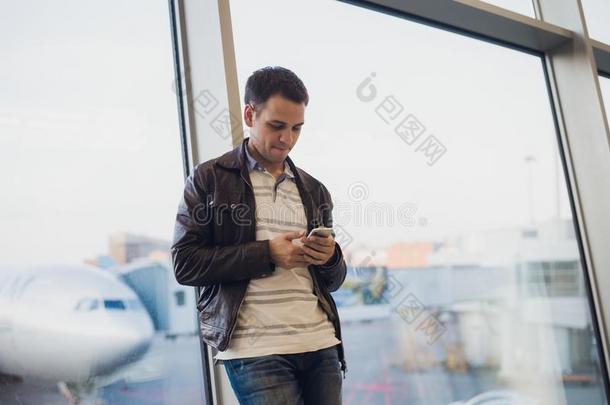 旅行支票里面的<strong>机场</strong>末期的.年幼的男人使用可移动的电话一