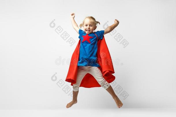 很兴奋的小的女孩打扮好的喜欢超级英雄用于跳跃的alongsid
