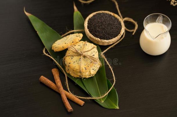 芝麻甜饼干,芝麻和奶向黑的木制的背景