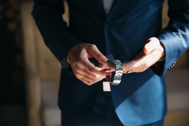 男人采用蓝色短上衣和插于钮孔上之花穿着腕表.观念