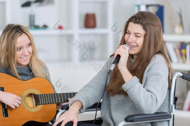 时髦的女孩向轮椅唱歌和朋友