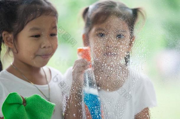 两个亚洲人小的小孩女儿帮助父亲向干净的窗