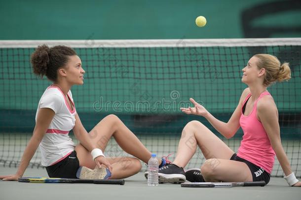 女人坐在旁边网球法院网投掷运动球进入中天空