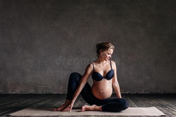 年幼的美丽的怀孕的瑜伽使摆姿势采用工作室
