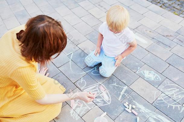 小的男孩绘画和制造白色或彩色粉笔的白垩向沥青