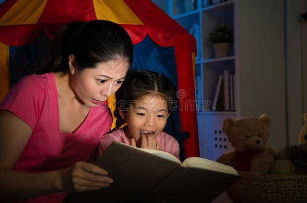 母亲和漂亮的年轻小孩阅读故事玩具书