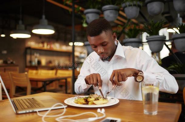 非洲男人aux.用以构成完成式及完成式的不定式正餐在咖啡馆后的使工作和便携式电脑.