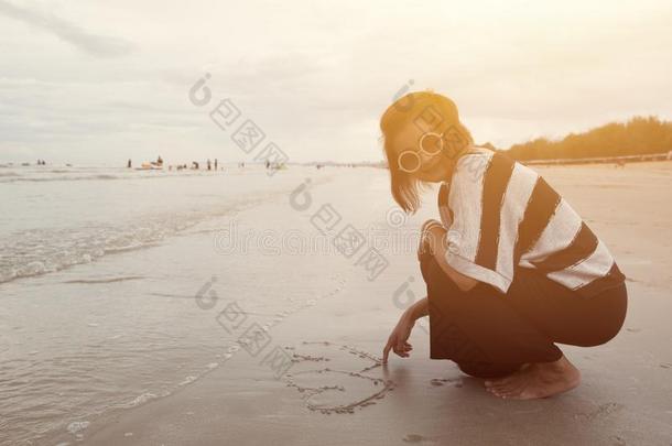因迪亚洲人女人微笑绘画心形状向沙海滩