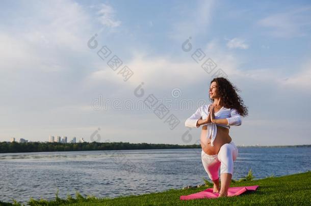 年幼的怀孕的女人做瑜伽在户外