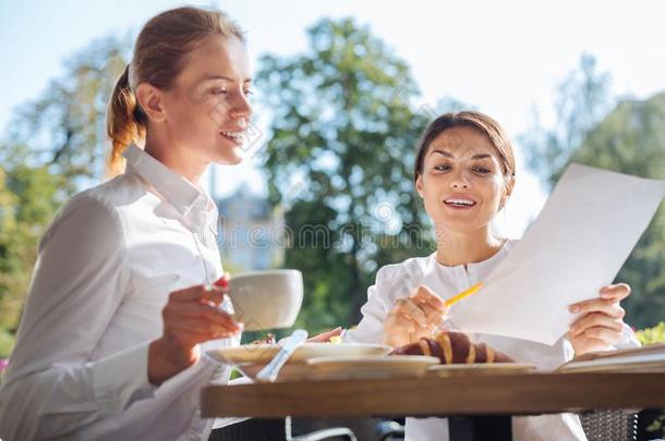 可爱的女人讲解资料向打印出来的资料向同事采用咖啡馆