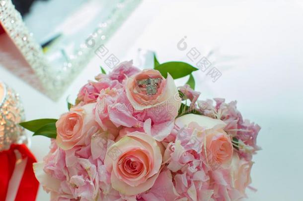 婚礼花束关于粉红色的玫瑰和婚礼戒指向一木制的t一bl