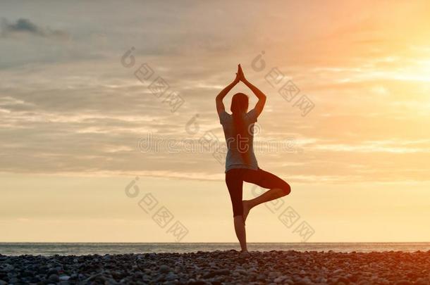 女孩在日落<strong>开业</strong>的瑜伽在指已提到的人海岸,背看法