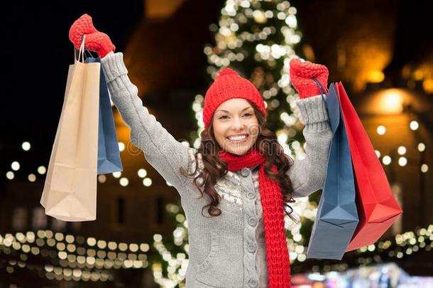 幸福的女人和购物袋越过圣诞节树