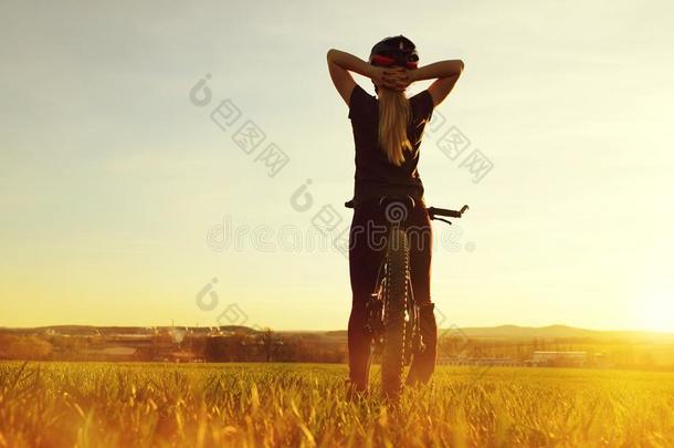 女孩向一自行车采用指已提到的人日落.