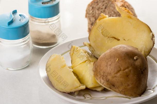 煮熟的马铃薯向指已提到的人盘子和盐和胡椒和面包