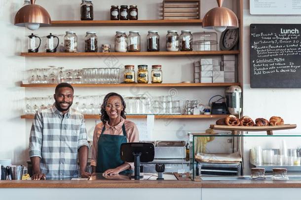 两个微笑的年幼的非洲的企业家起立在他们的面包房