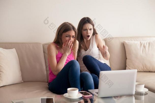 两个恐惧的女朋友尖叫的在期间观察恐怖电影.