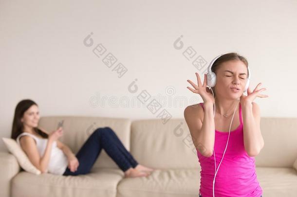 年幼的女孩收听的音乐和她女孩friend令人轻松的向沙发.