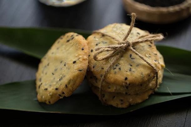 芝麻甜饼干,芝麻和奶向黑的木制的背景