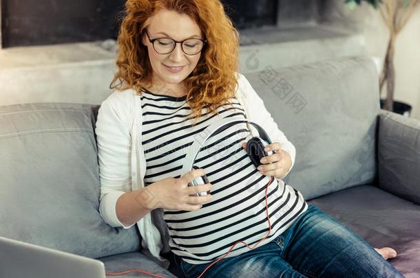 欢乐的怀孕的女人遵守耳机采用手