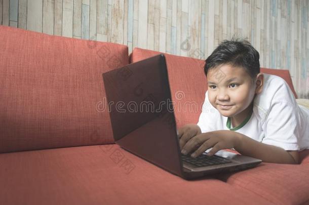 年幼的亚洲人男孩使用便携式电脑计算机向一sof一一t家.