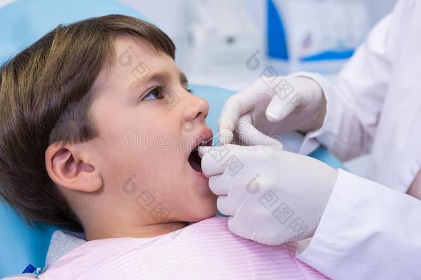 男孩接受牙齿的治疗在旁边牙科医生