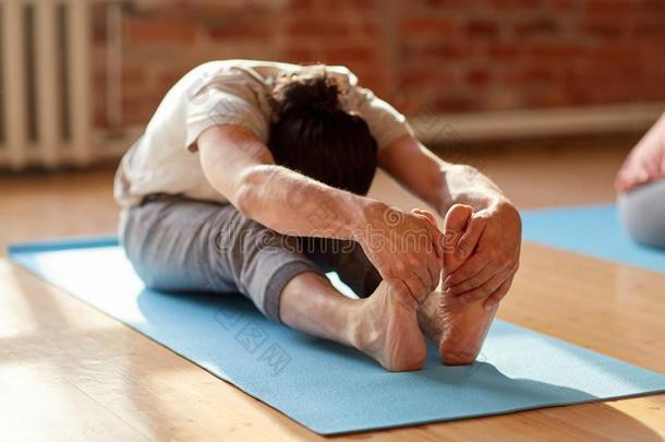 男人做瑜伽前进地弯曲在工作室或健身房
