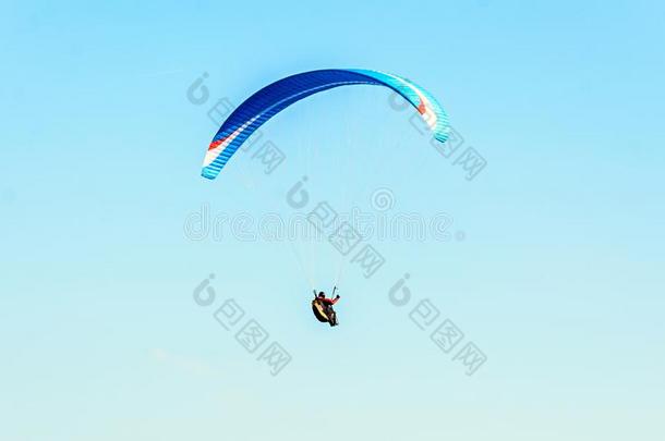 男人滑翔伞运动和蓝色降落伞在上面水海,清楚的天