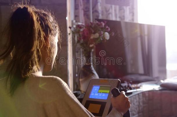 黑头发的妇女女人开业的向指已提到的人自行车模拟装置在旁边窗看着