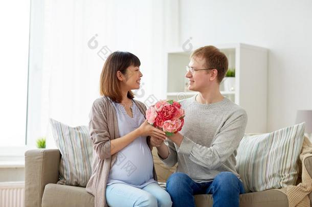 幸福的丈夫礼物花向他的怀孕的妻子