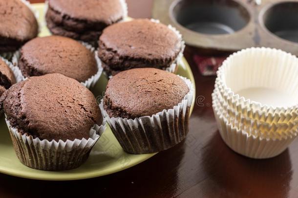 新鲜的烘烤制作的巧克力杯子蛋糕向指已提到的人盘子和烘焙盘子采用
