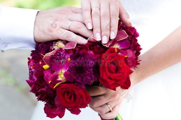 手和戒指向红红火火的婚礼花束