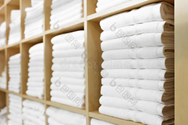 新鲜的白色的旅馆毛巾折叠的和堆积向一架子