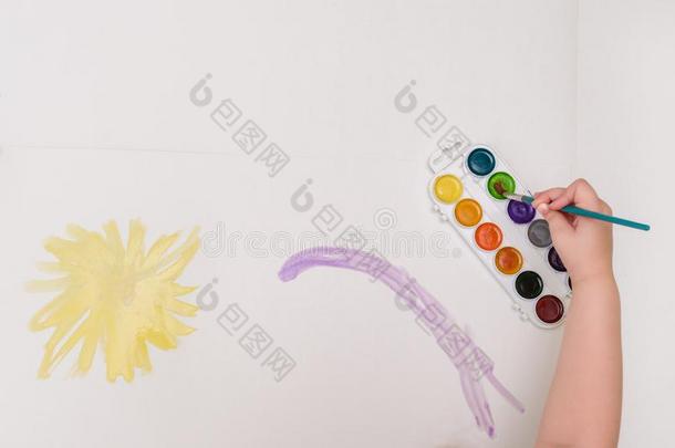 小孩手和擦绘画向白色的纸黄色的太阳