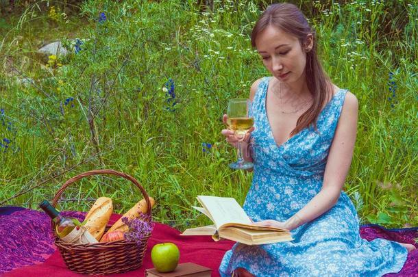 年幼的女人采用浪漫的蓝色衣服在一野餐郊游.女孩是（be的三单形式re一d采用g