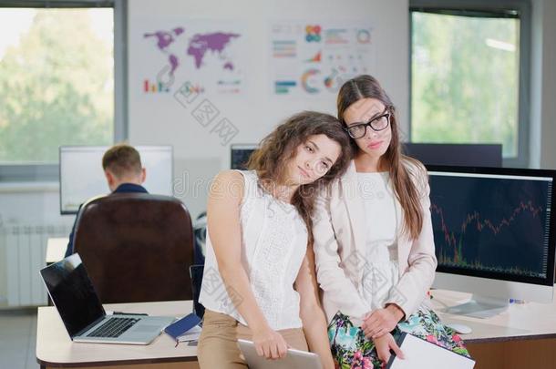 两个年幼的商业女儿采用白色的短上衣在指已提到的人办公室是使疲惫