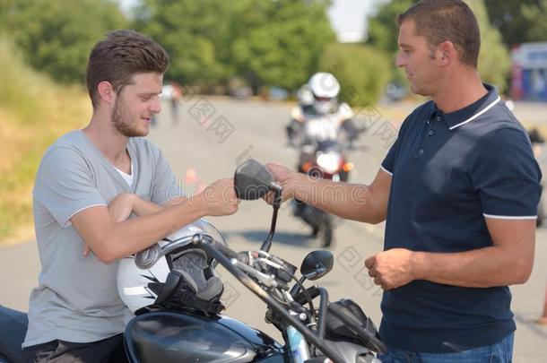 年幼的男人向摩托车讲话和指导者