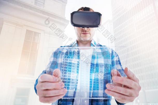 有刚毛的男人有样子的在透明的碑通过VirtualReality虚拟现实戴在头上的耳机或听筒