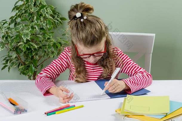 一较年幼的女学生和眼镜写某物和她<strong>左边</strong>的