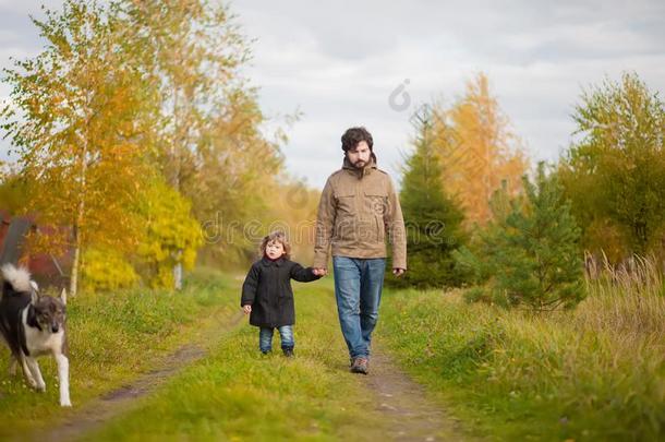 父亲和女儿步行同时和狗,秋一天.