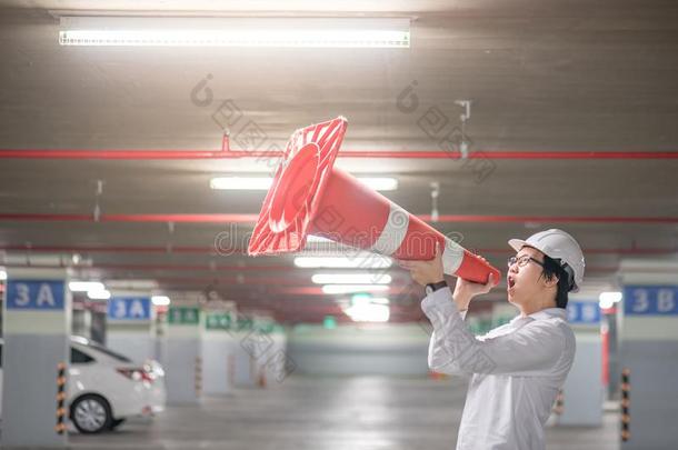 年幼的亚洲人工程师叫喊虽然交通安全圆锥体采用帕基